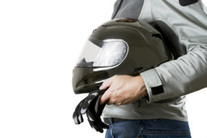 Torso of a motorcyclist in protective gear holding a helmet and gloves. Isolated on white background